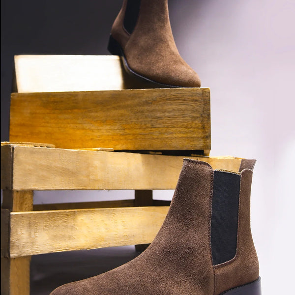 A men's luxury suede leather Chelsea boot with a mid heel and elastic side panels, in a brown color.
