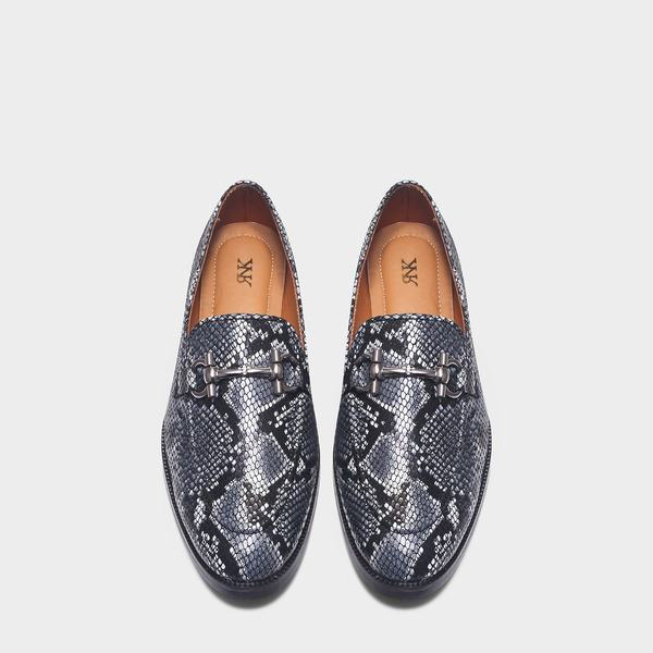 Pair of snake print horsebit loafers on a light gray background