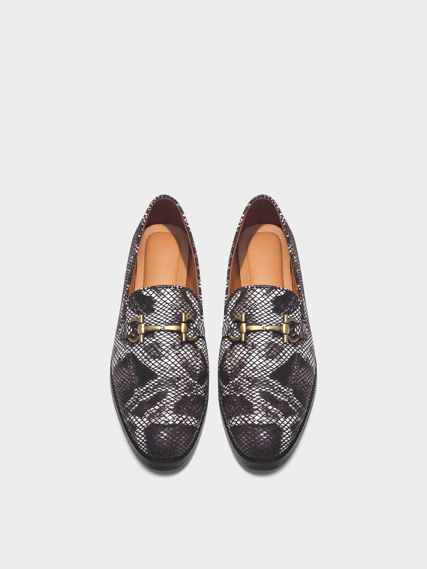 Pair of patterned loafers with gold accents on a light gray background