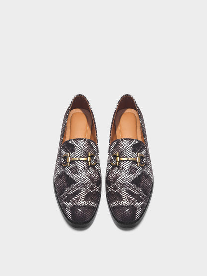 Pair of patterned loafers with gold accents on a light gray background