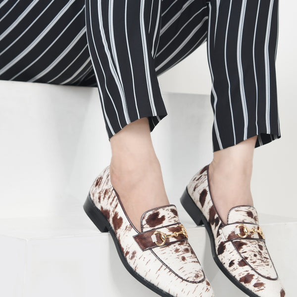 Person wearing patterned loafers and black and white striped pants on a light background