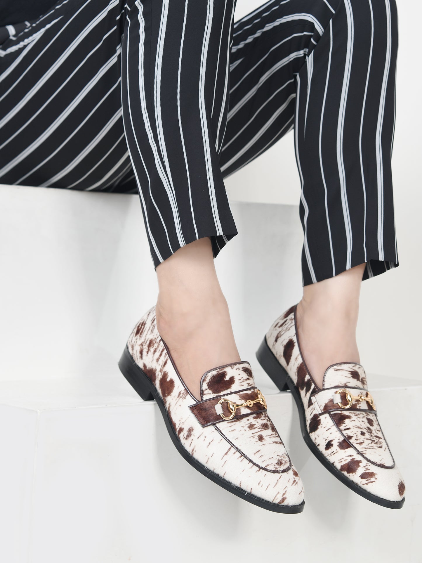 Person wearing patterned loafers and black and white striped pants on a light background
