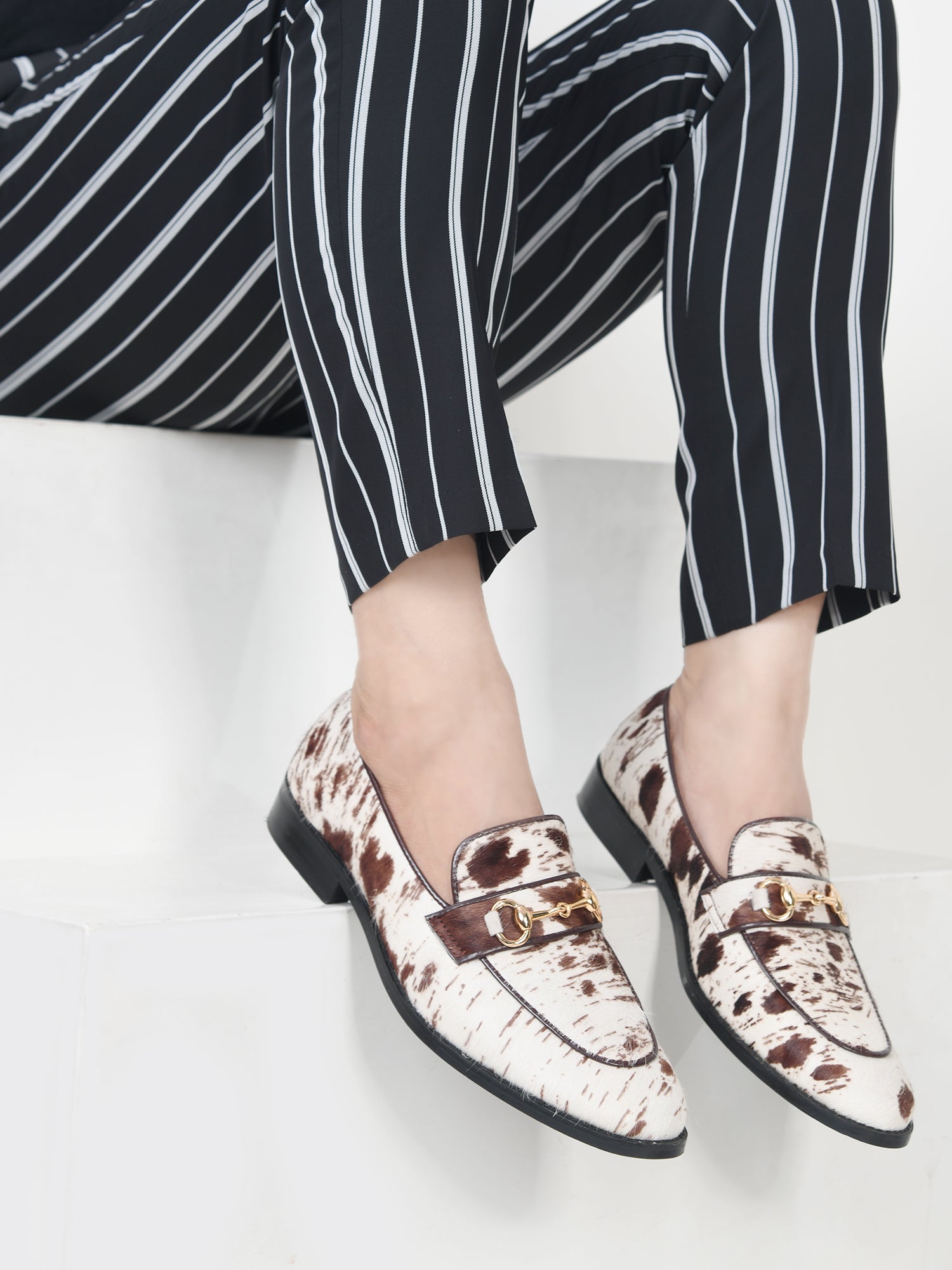 Person wearing patterned loafers and black and white striped pants on a light background