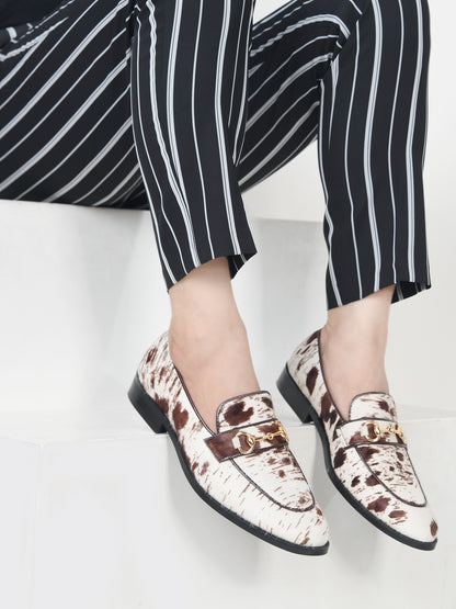 Person wearing patterned loafers and black and white striped pants on a light background
