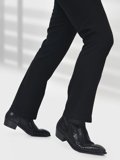 Black dress shoes with textured sole worn with black pants on a white background