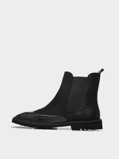 Black Chelsea boot on a light gray background