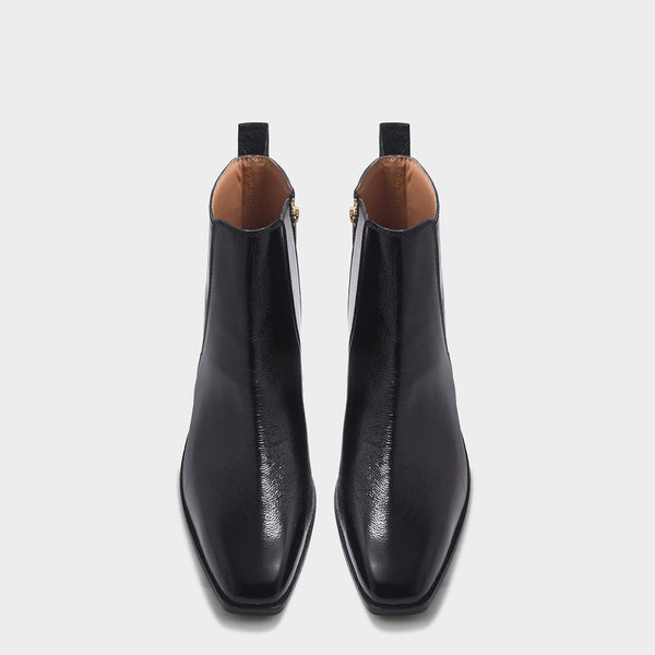 Pair of a black patent leather boots with side zipper on a mid heel