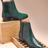 A green leather side zip boot with a crocodile pattern and a Cuban heel.