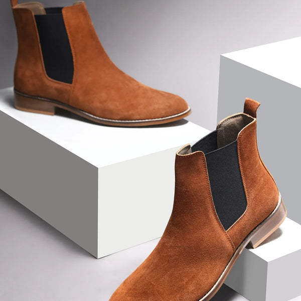 A men's luxury suede leather Chelsea boot with a mid heel and elastic side panels, in a tan color.