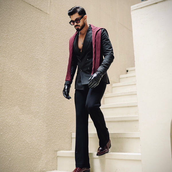 Men’s luxury cherry red pointed-toe Chelsea boots in patent leather with side zip closure, worn with black trousers and leather gloves; sleek and stylish footwear ideal for formal and high-fashion outfits.