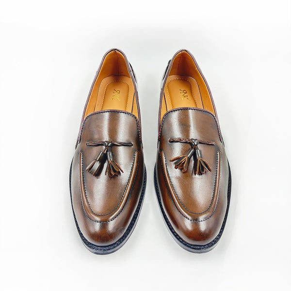 Pair of brown leather loafers with tassels on a white background